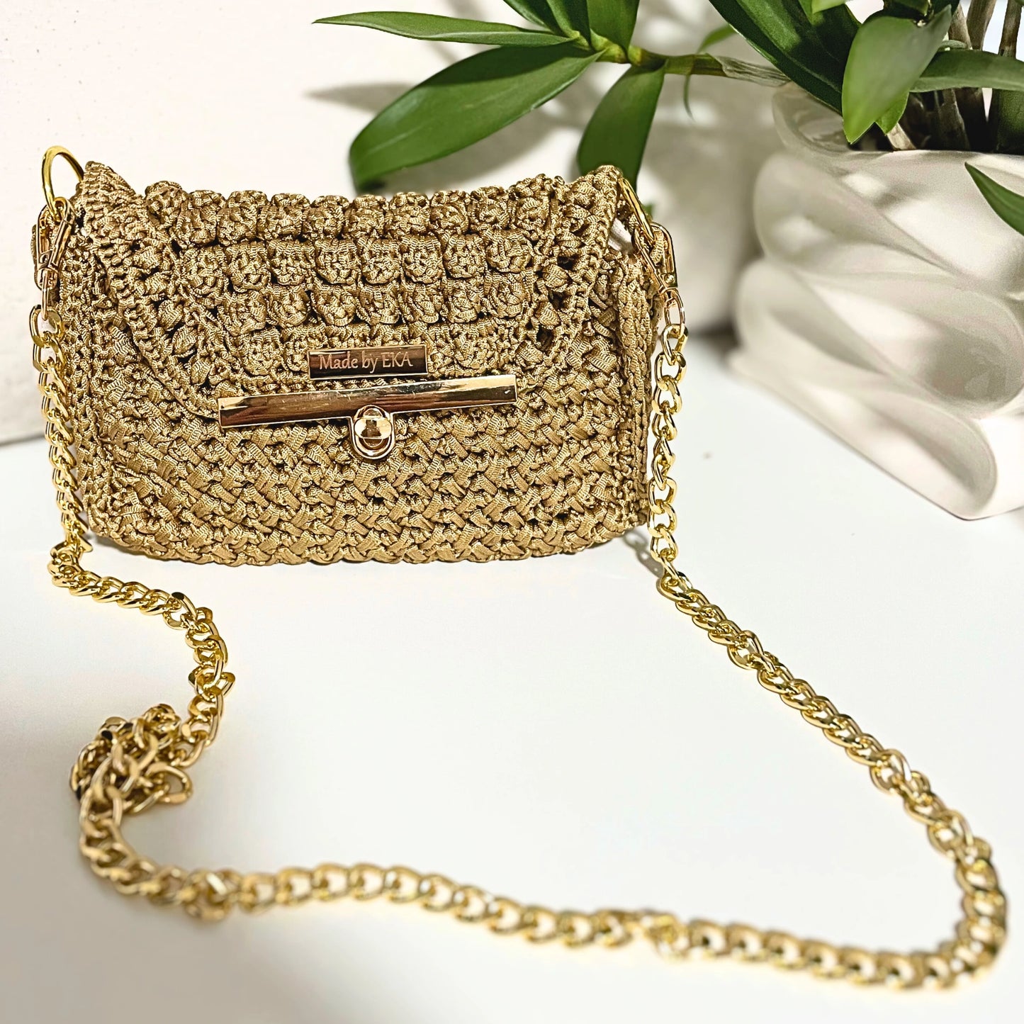 Crocheted handbag with gold chain strap on a light background