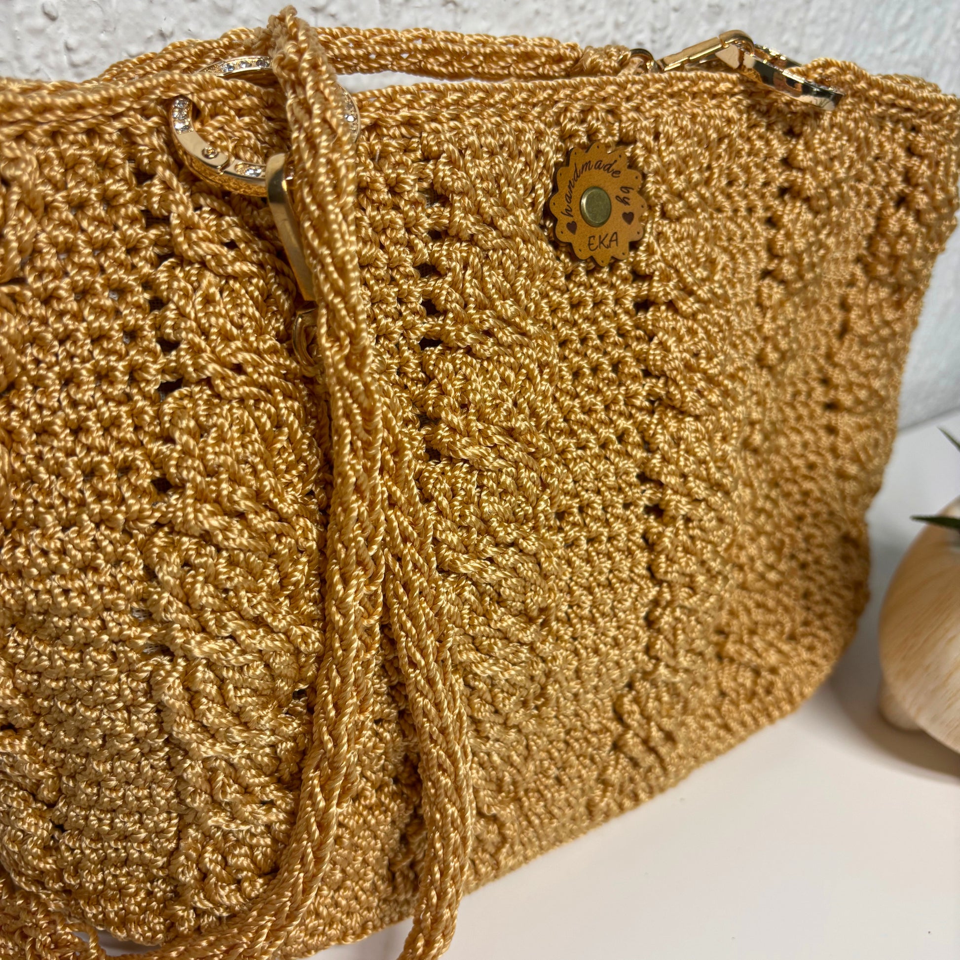 Gold crochet bag with decorative logo on a light background