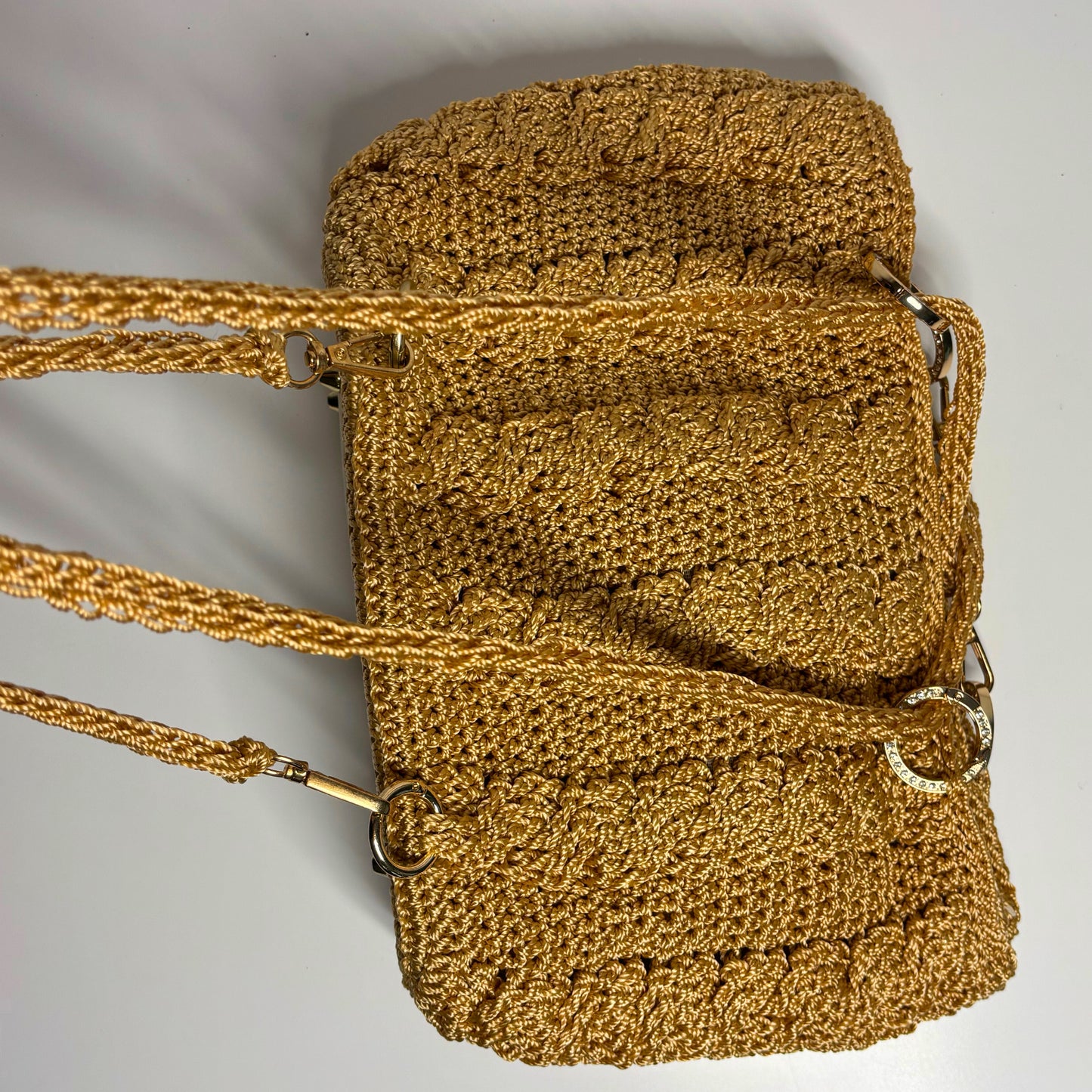 Gold textured handbag with a strap on a light gray background