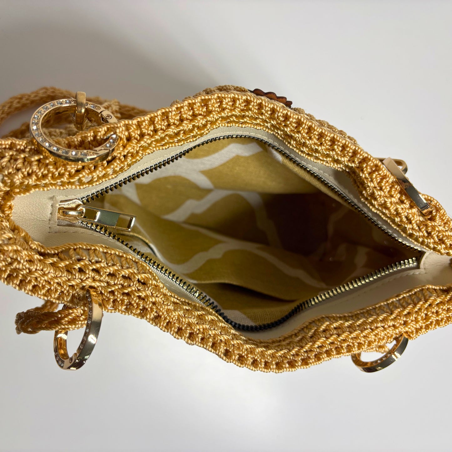 Gold crocheted bag with a zipper on a light gray background