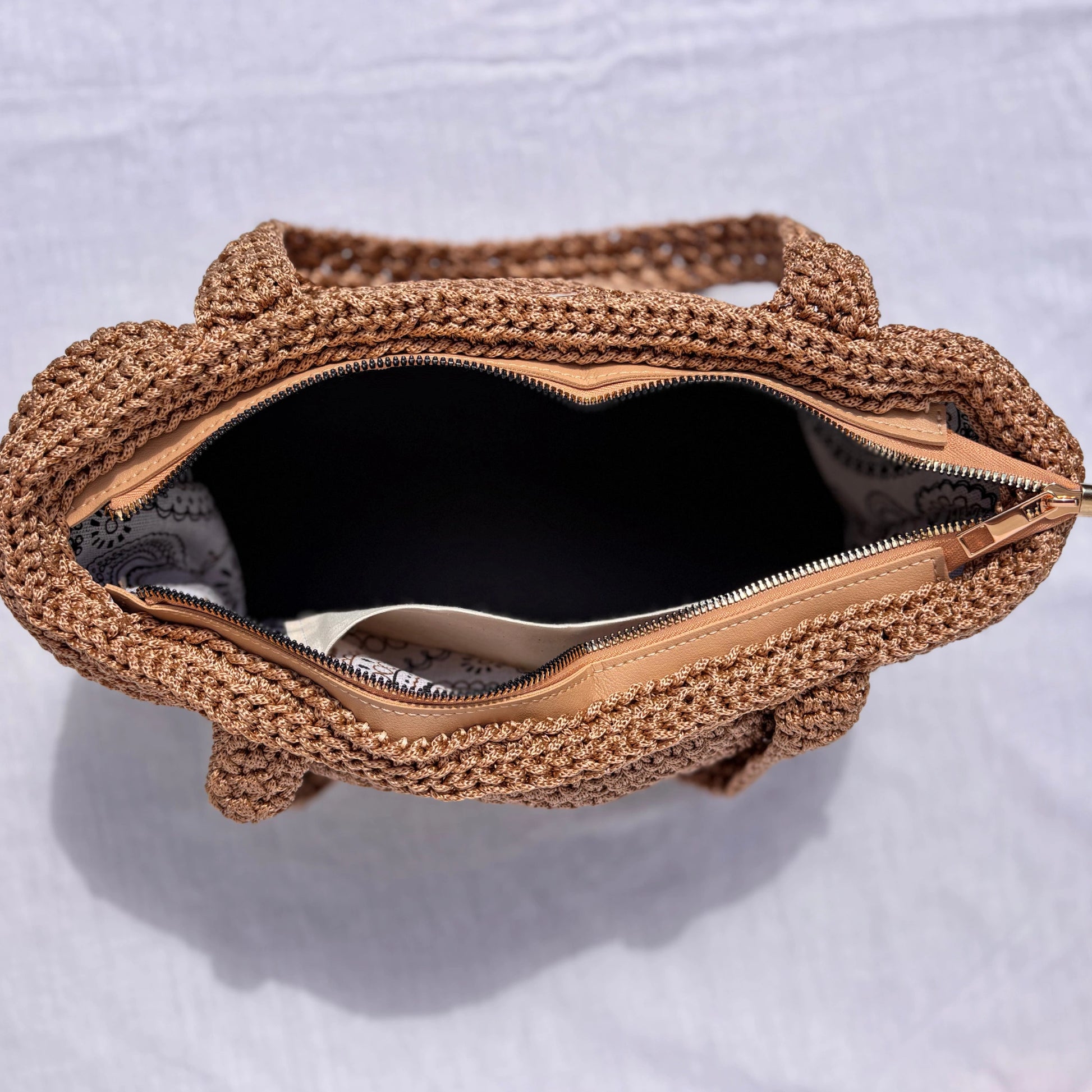 Top-down view looking directly into the open Elena purse, displaying the zip closure, patterned fabric lining, and inner slip pocket.