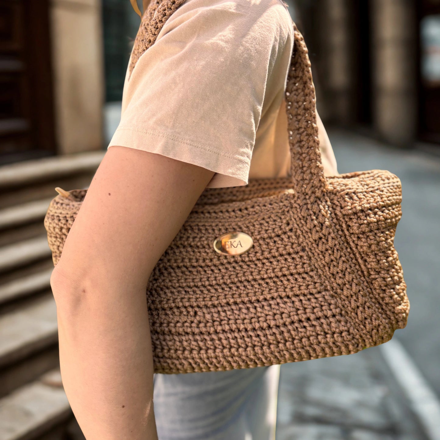 Model wearing the bronze-gold Elena crochet shoulder bag over the shoulder, demonstrating its size, slouchy drop, and everyday fit.