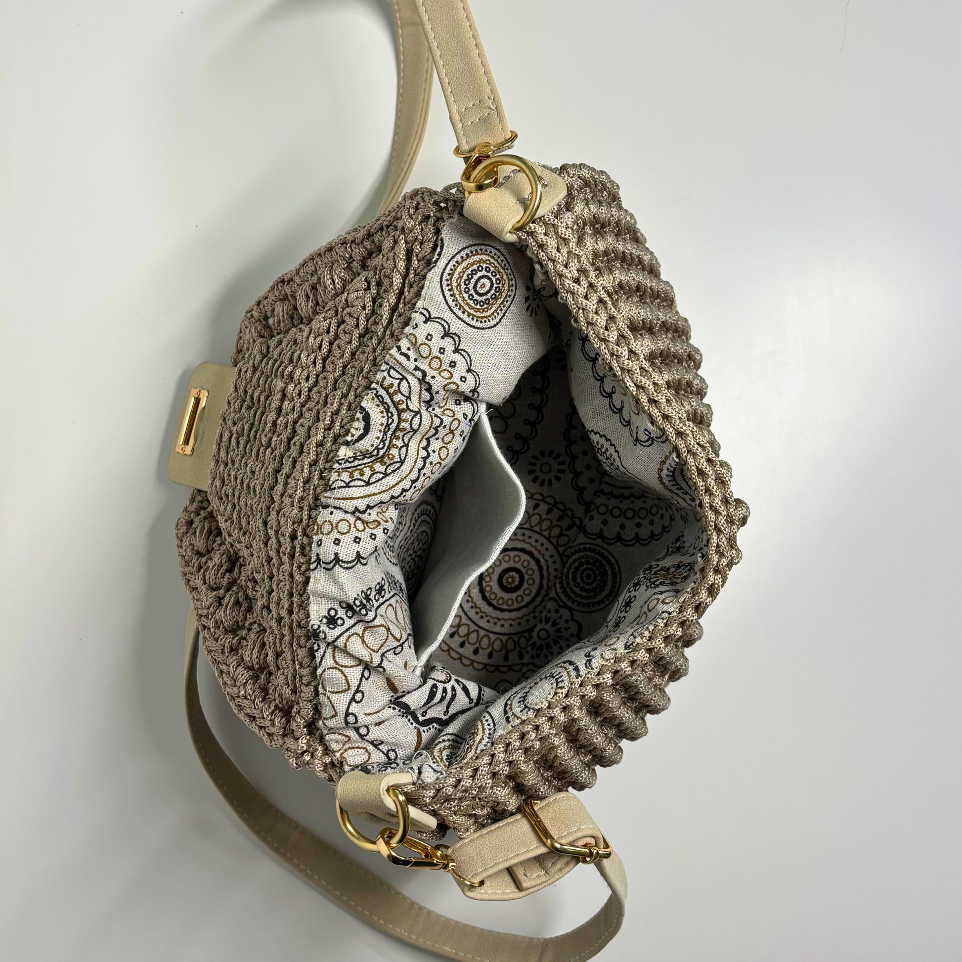 Crocheted beige bag with gold accents on a light gray background