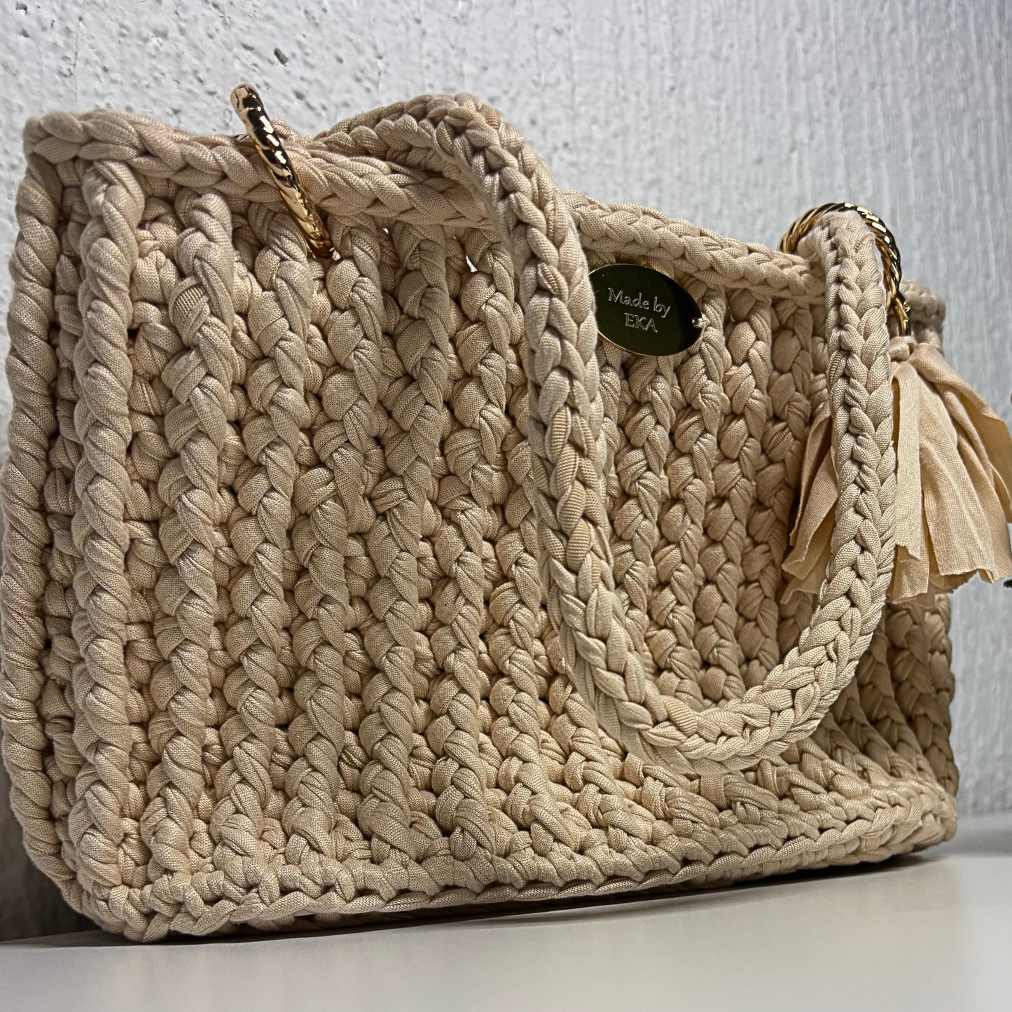 Beige handbag with a tassel on a white surface