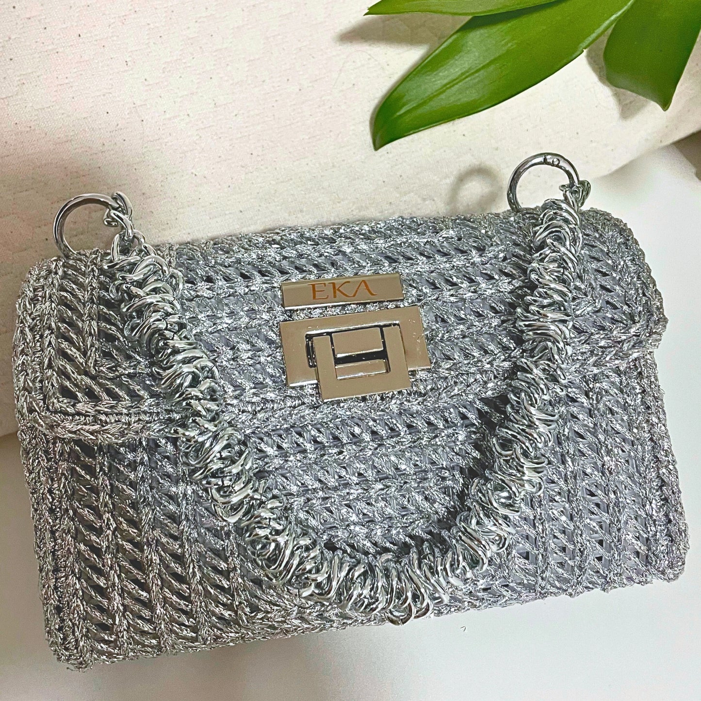 Silver textured handbag with a brand Eka logo on a light background