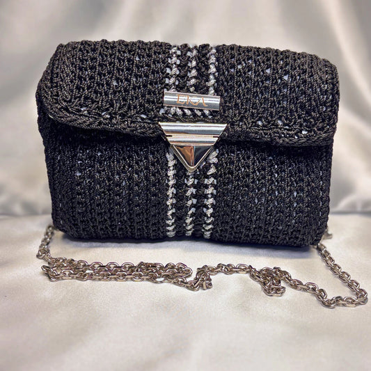 Black textured handbag with chain detail on a light background