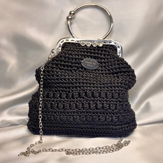 Black crocheted handbag with a silver chain and clasp on a white background