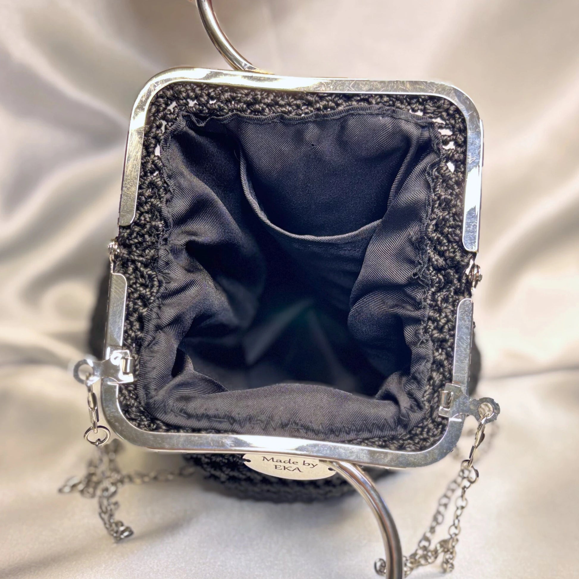 Black clutch purse with black interior on a satin background