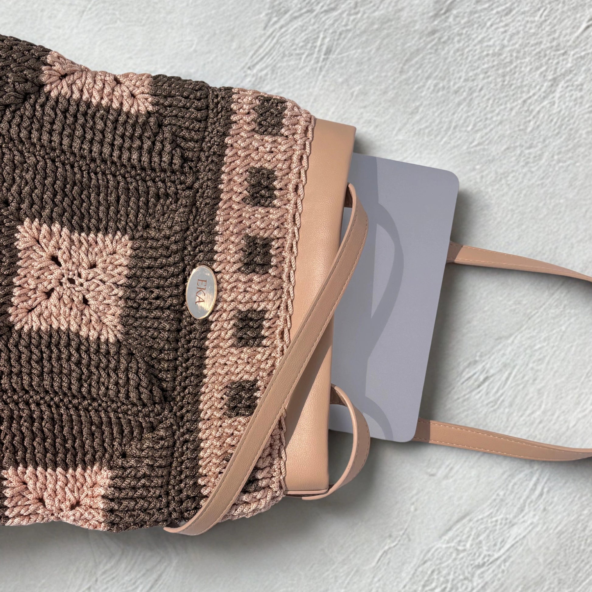Top view of a silver laptop sliding easily into the open Fiona crochet tote bag, demonstrating its spacious interior size.
