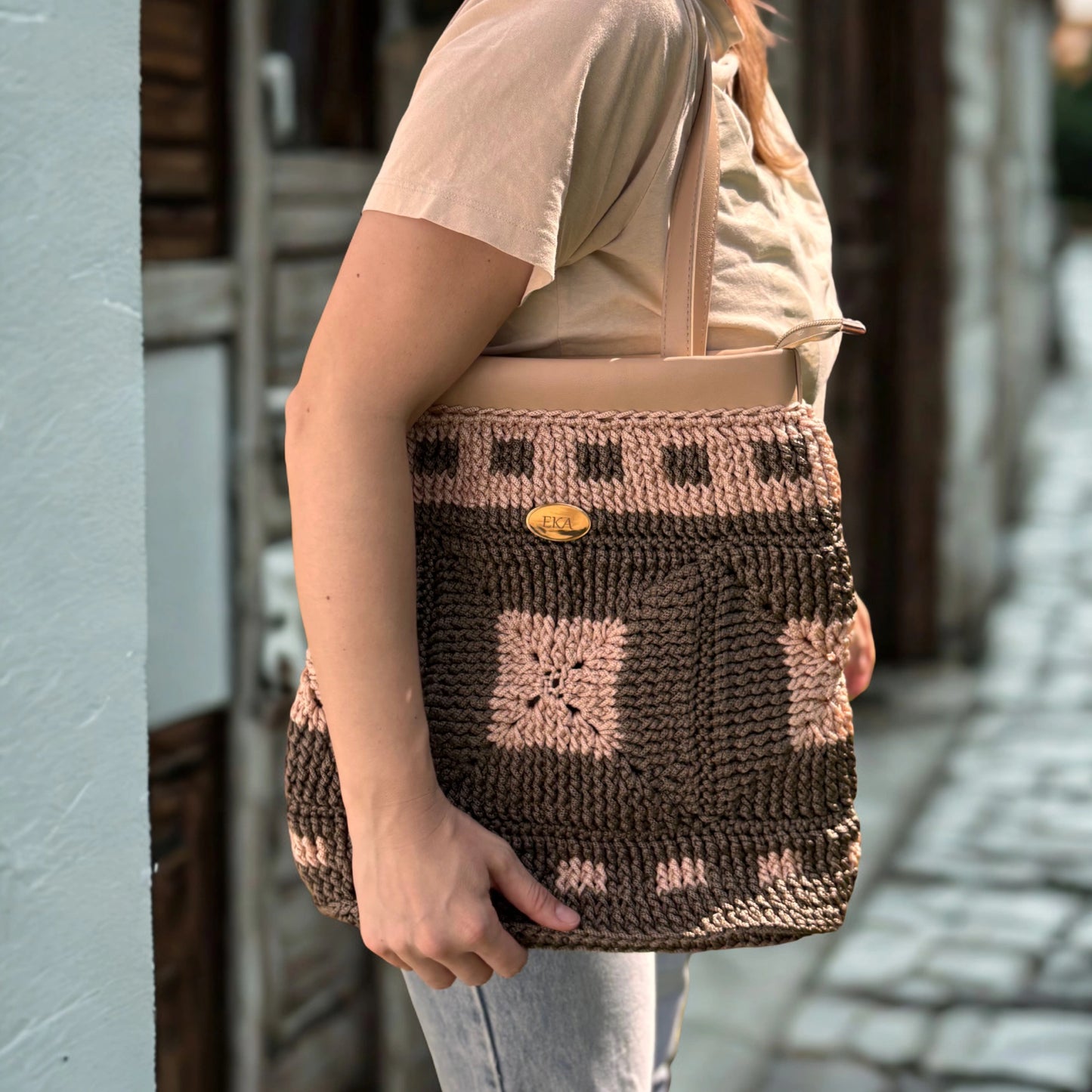 Model carrying the Fiona brown and beige crochet tote over the shoulder while walking outdoors, showing its full length and everyday fit.