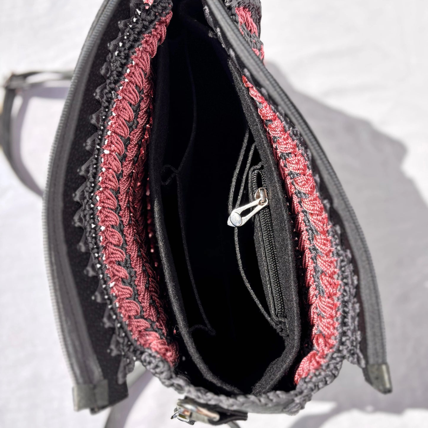Looking down into the open Gloria bag, revealing the black interior lining, an internal zippered pocket, and open slip compartments.