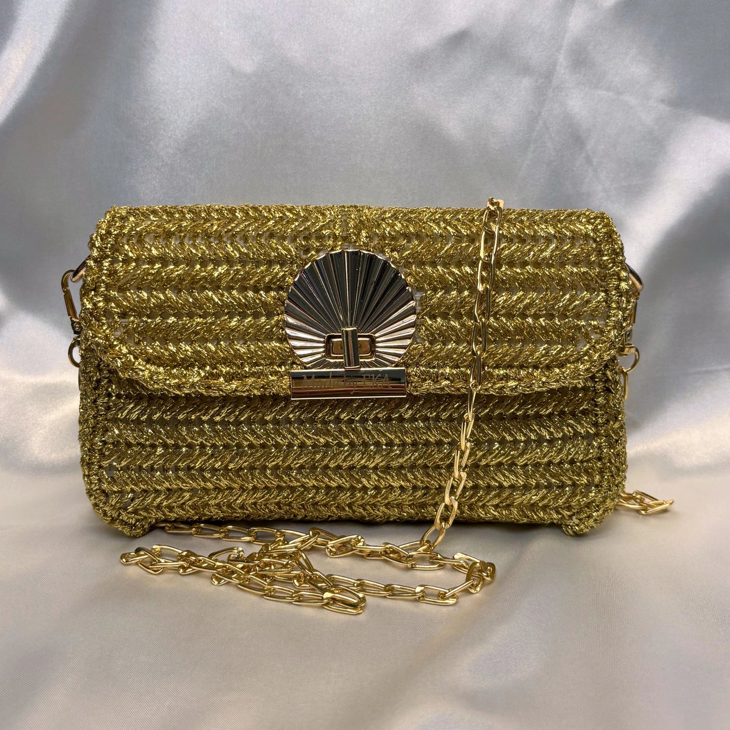 Gold crochet handbag with a chain strap on a light gray background