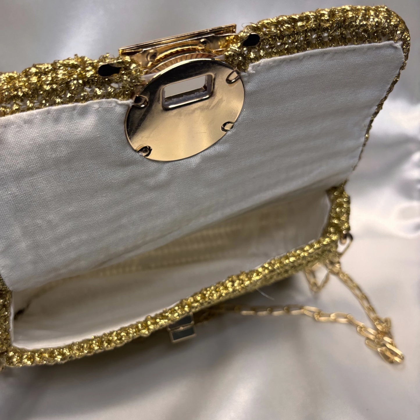 Gold clutch with embellishments on a reflective surface
