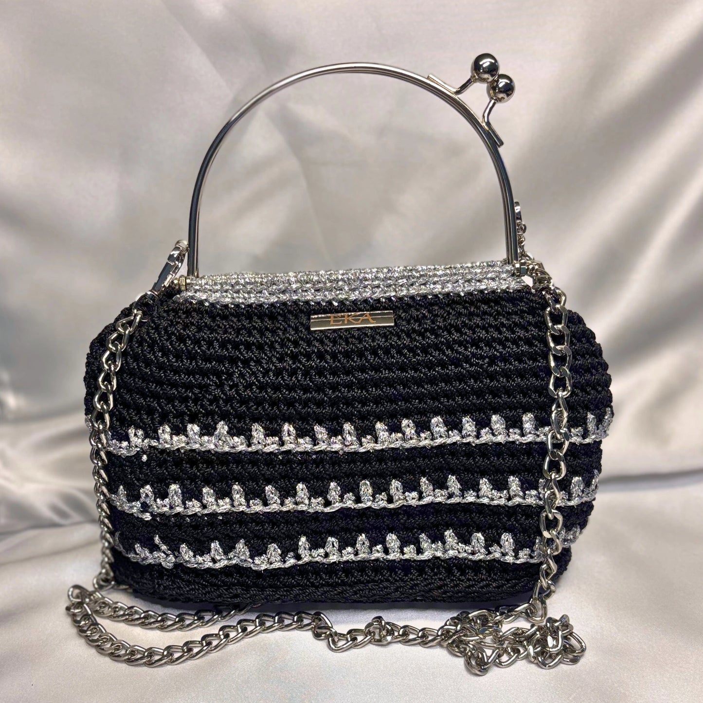 Black handbag with silver chain and embellishments on a white background