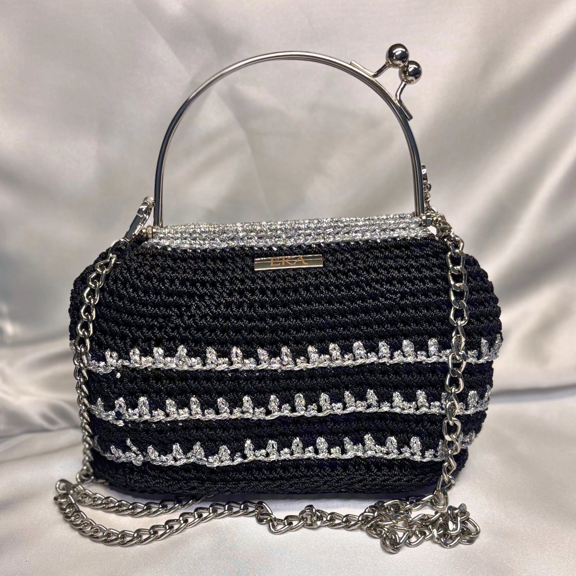 Black handbag with silver chain and embellishments on a white background