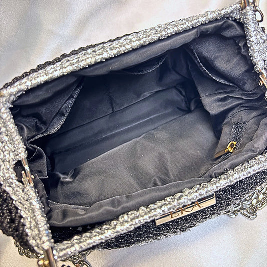 Close-up of a sparkling handbag with a gold clasp on a light gray background