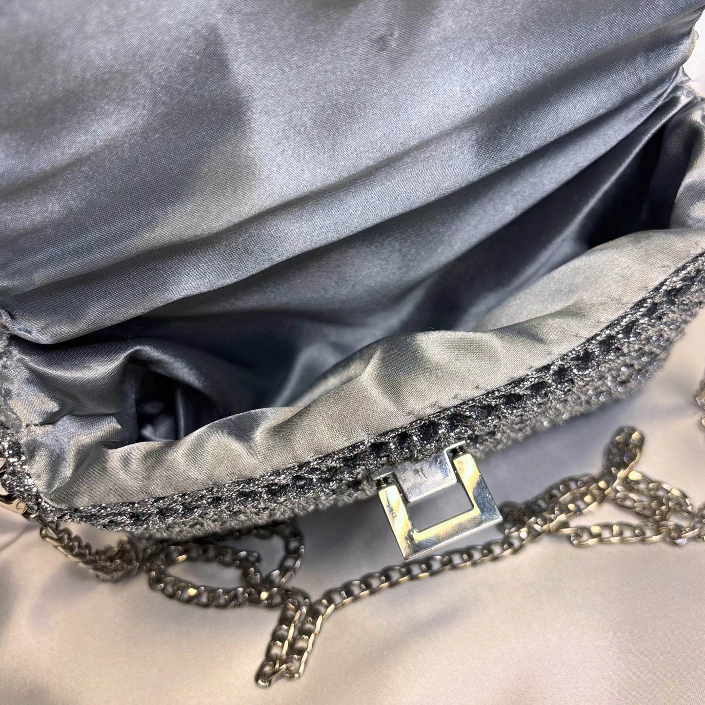 Close-up of a silver handbag with a chain detail on a light gray background
