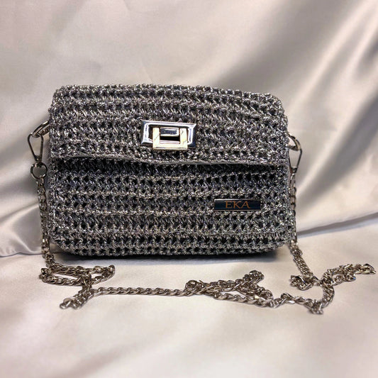 Silver crochet handbag with a chain strap on a light gray background