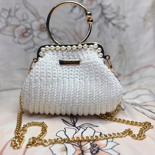 White beaded handbag with gold chain and handle on a floral background