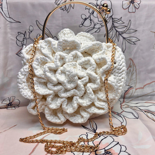 White textured handbag with gold chain on a floral-patterned background