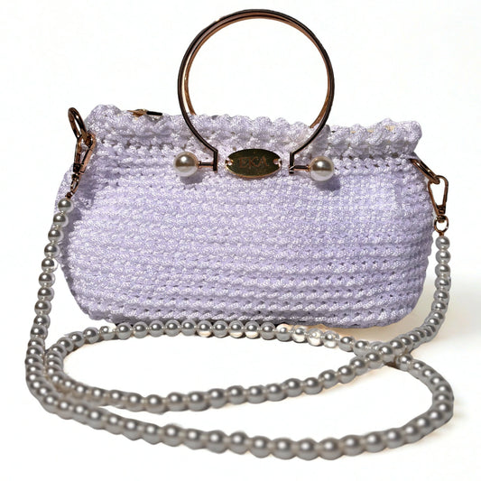 A white crocheted handbag with a gold-tone metal ring handle, pearl accents, and a long silver pearl chain strap, shown on a plain white background.
