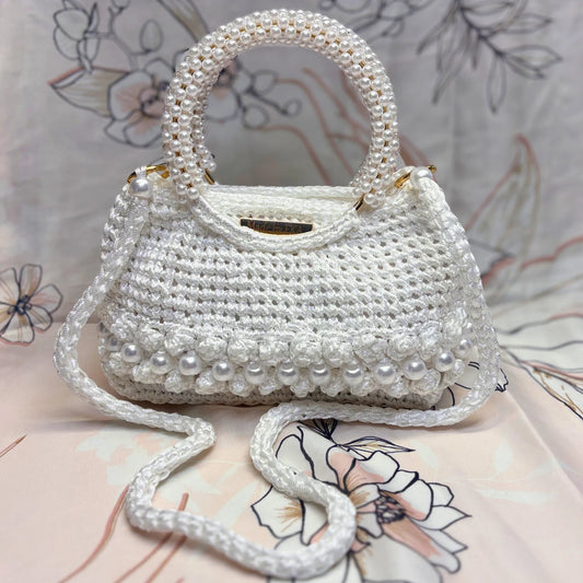 White handbag with pearl embellishments on a floral-patterned surface