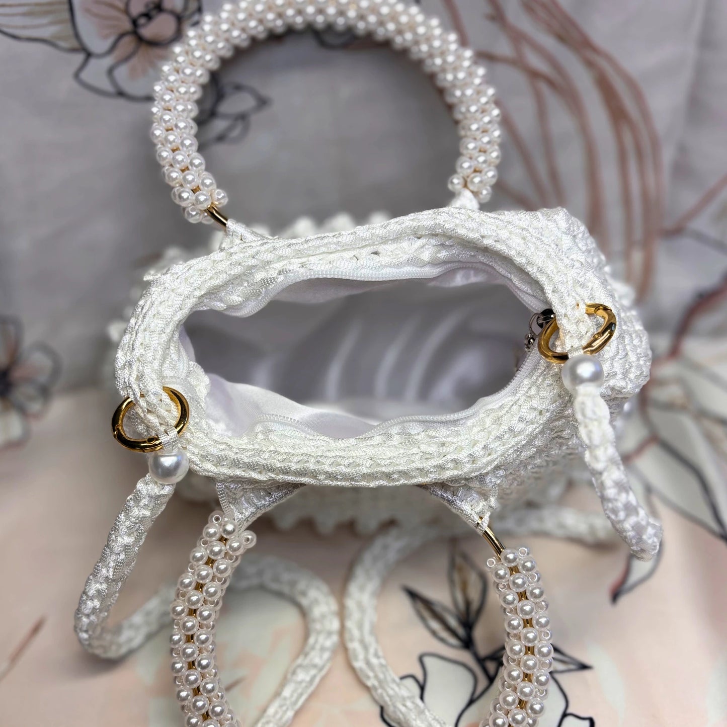 White handbag with pearl detailing on a floral background